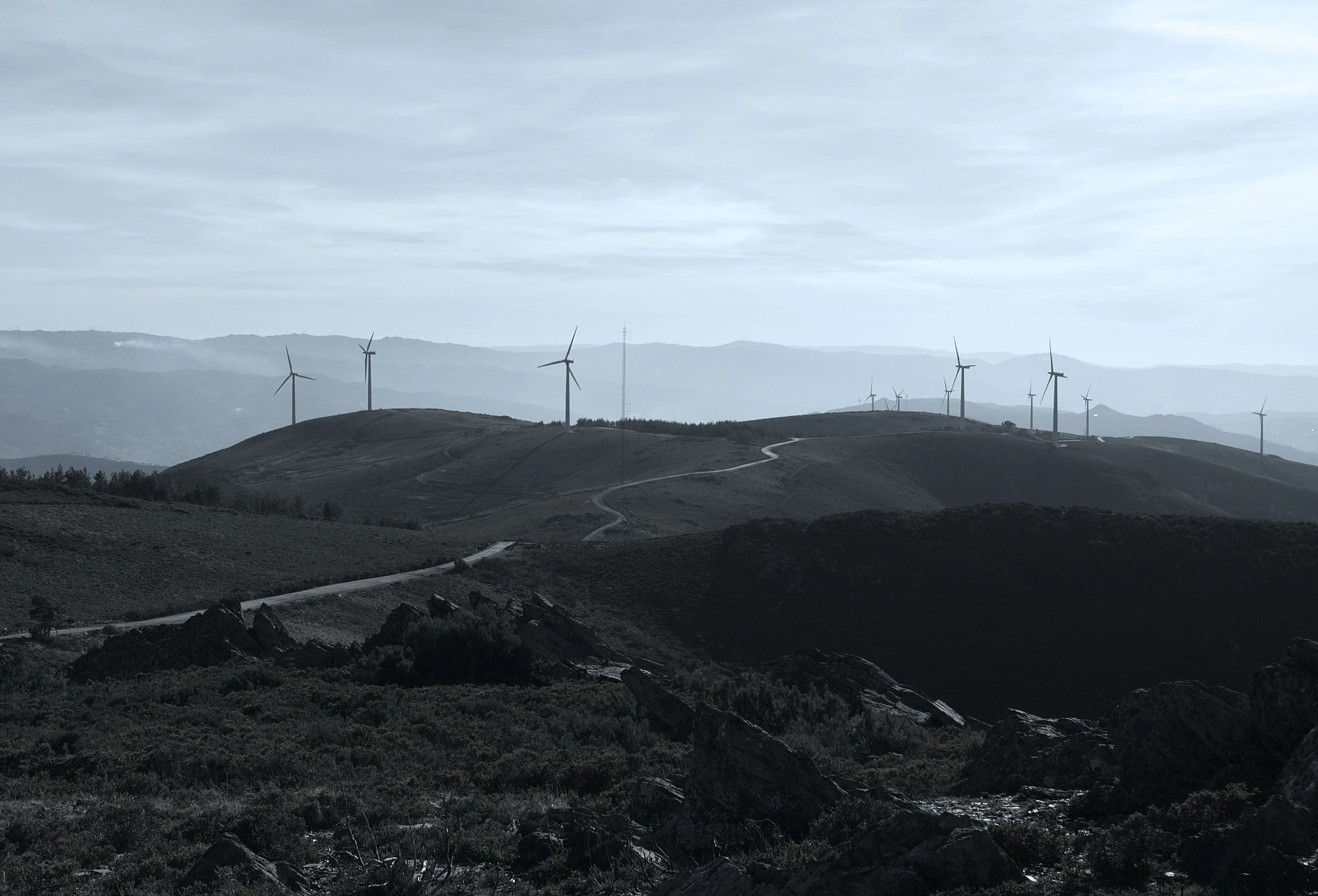 Wind turbines silhouetted across a hilly landscape