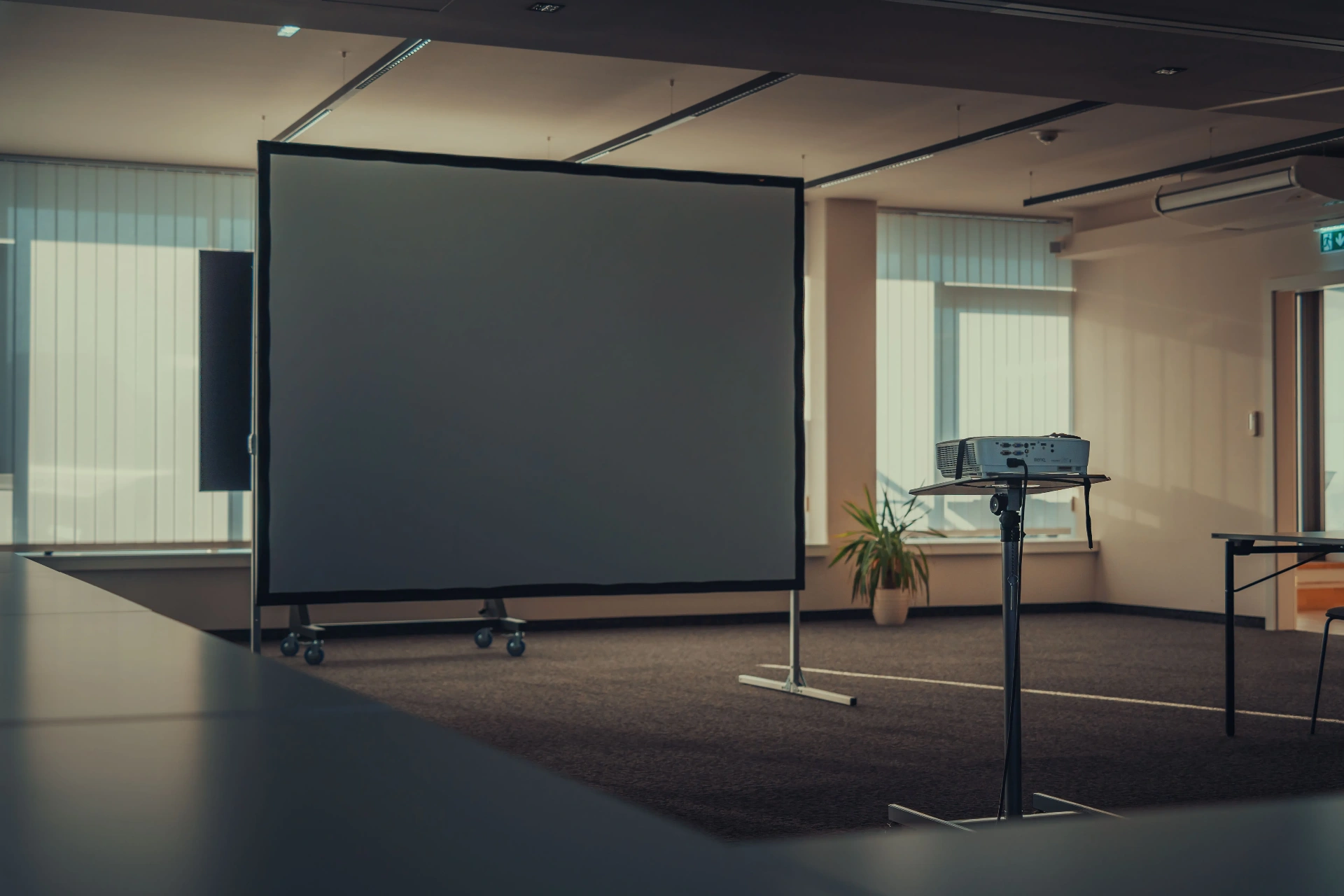 An empty projection screen and projector in a presentation room