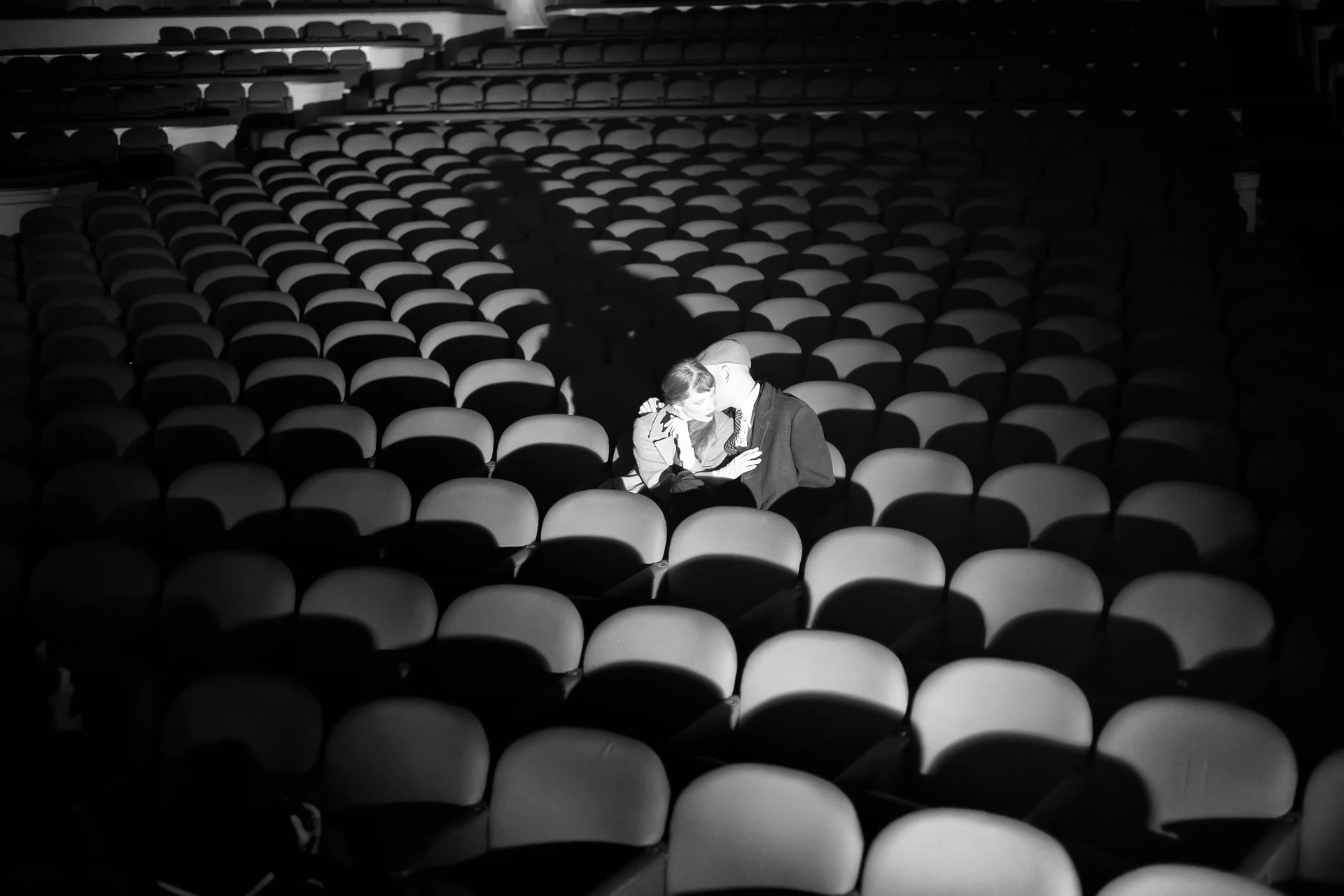 An almost empty theater auditorium with two people seated