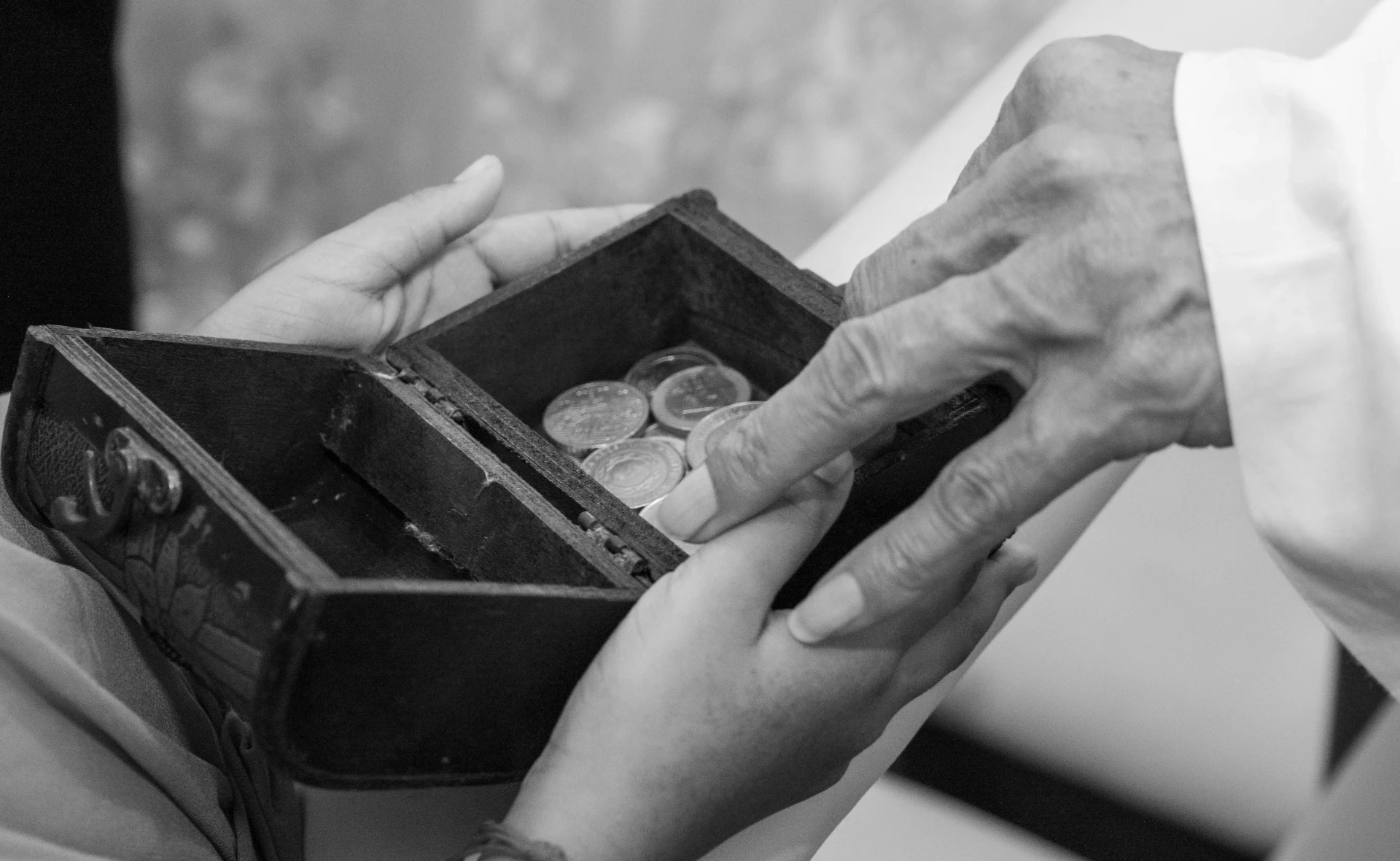 Two pairs of hands exchanging a small box of coins